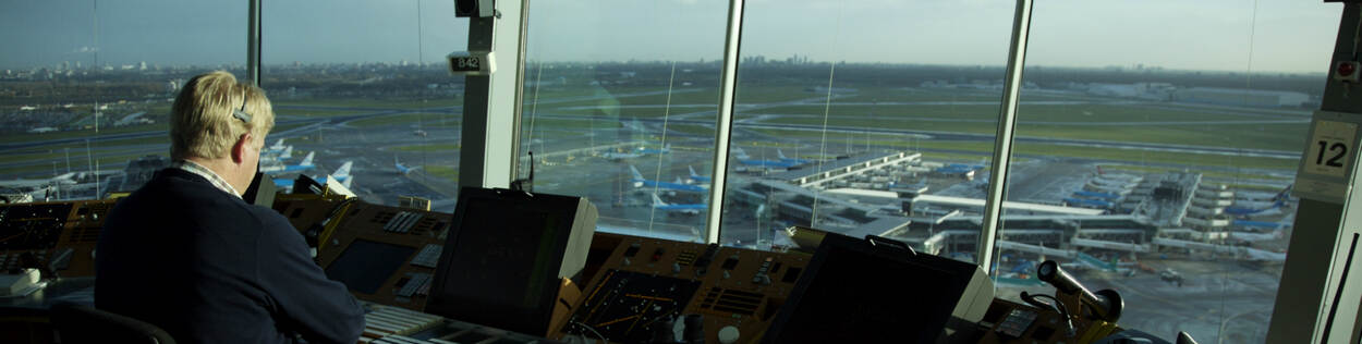 Air traffic controller in control tower with view of airport in the Netherlands