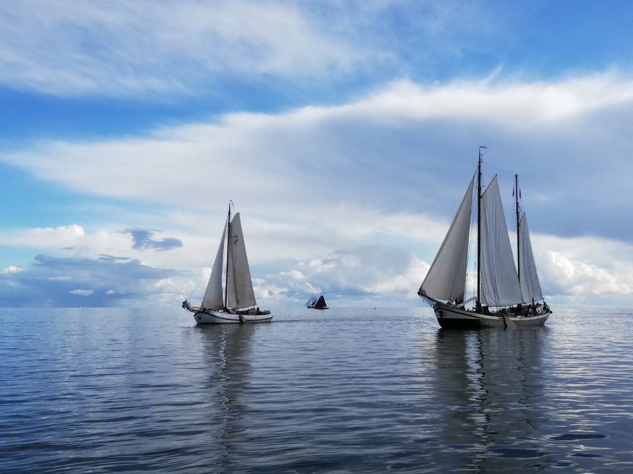 Historische zeilende passagiersschepen op het water onder een wolkenlucht