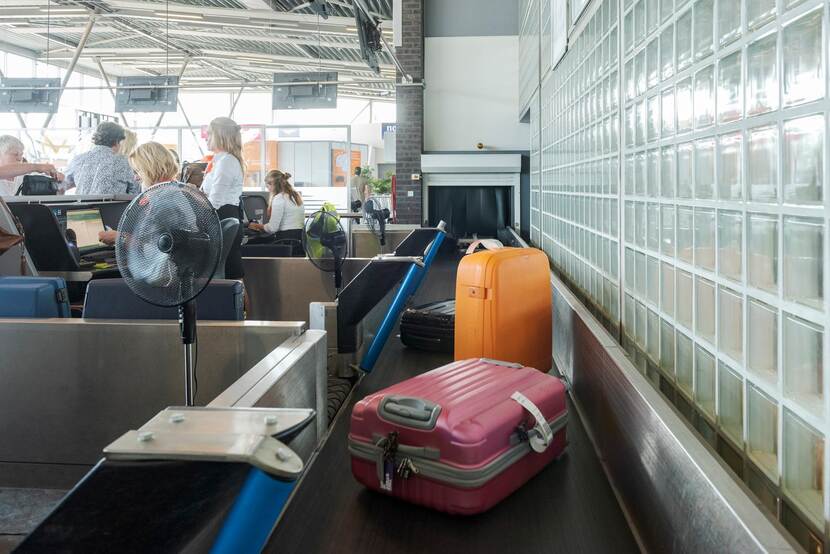 Koffers op transportband voor ingecheckte bagage op vliegveld Groningen Eelde.
